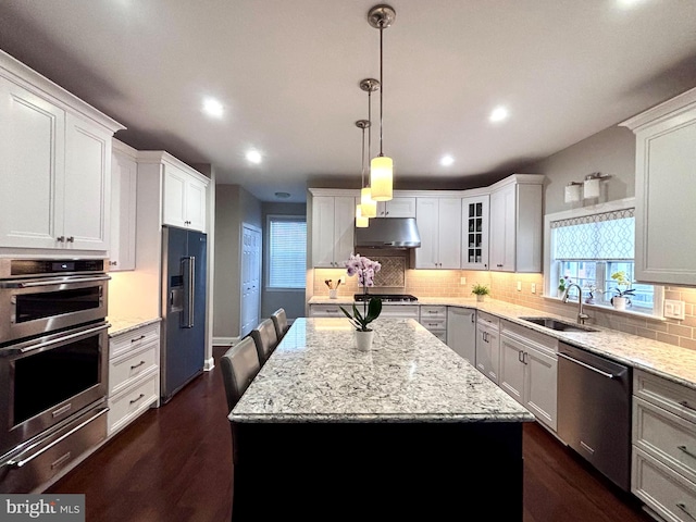 kitchen featuring pendant lighting, sink, appliances with stainless steel finishes, white cabinetry, and a center island