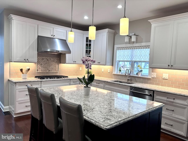 kitchen featuring sink, decorative light fixtures, appliances with stainless steel finishes, a kitchen island, and white cabinets