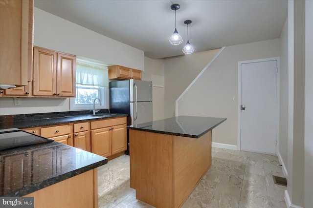 kitchen featuring dark stone counters, sink, pendant lighting, and a center island