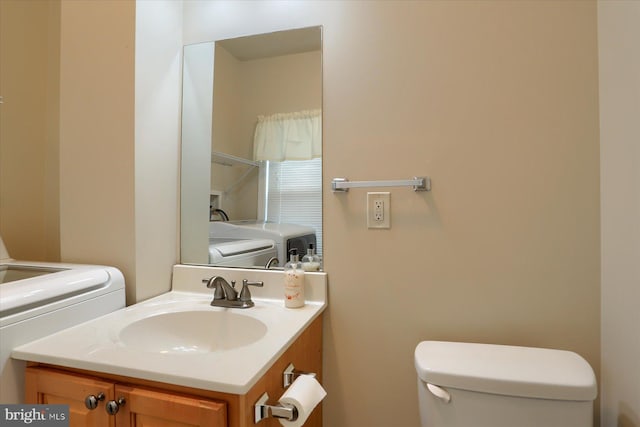 bathroom featuring toilet, vanity, and washing machine and dryer