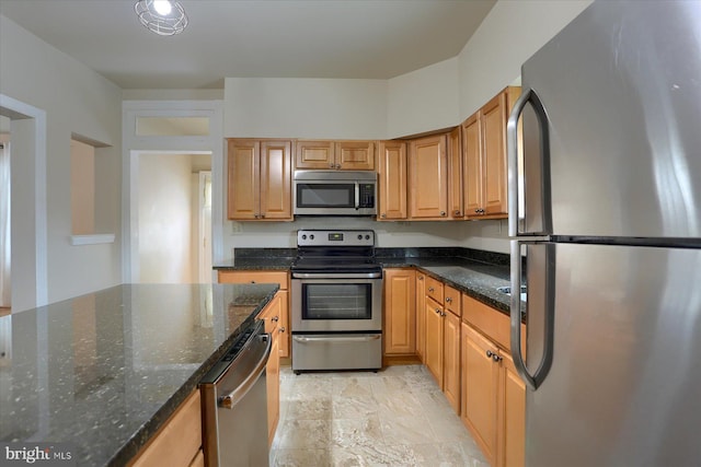 kitchen featuring stainless steel appliances and dark stone countertops