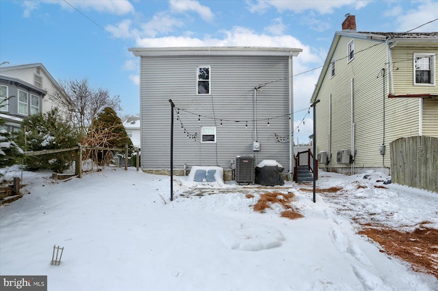 snow covered rear of property featuring cooling unit