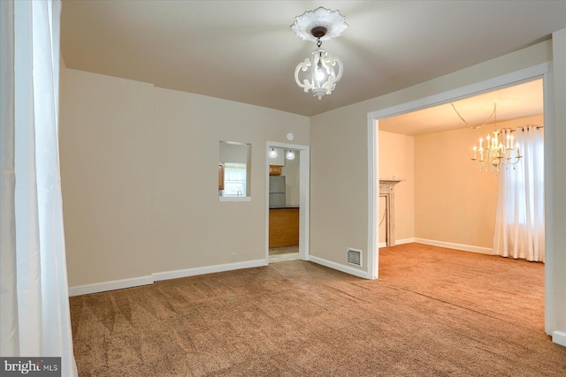 spare room with a chandelier and carpet flooring