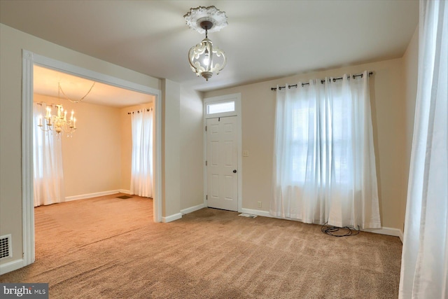 carpeted entrance foyer with plenty of natural light and a notable chandelier