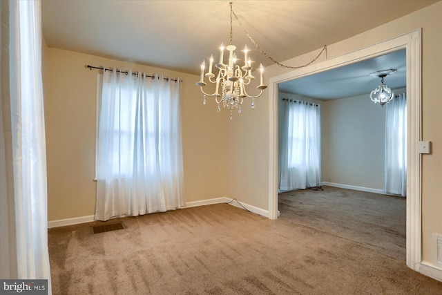 carpeted spare room with a notable chandelier