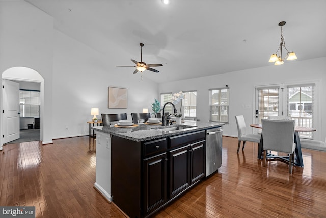 kitchen with dishwasher, dark hardwood / wood-style flooring, sink, light stone countertops, and a kitchen island with sink