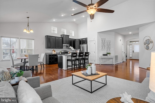 living room featuring ceiling fan with notable chandelier, high vaulted ceiling, and dark hardwood / wood-style floors