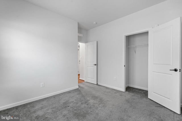 unfurnished bedroom featuring a closet and dark carpet