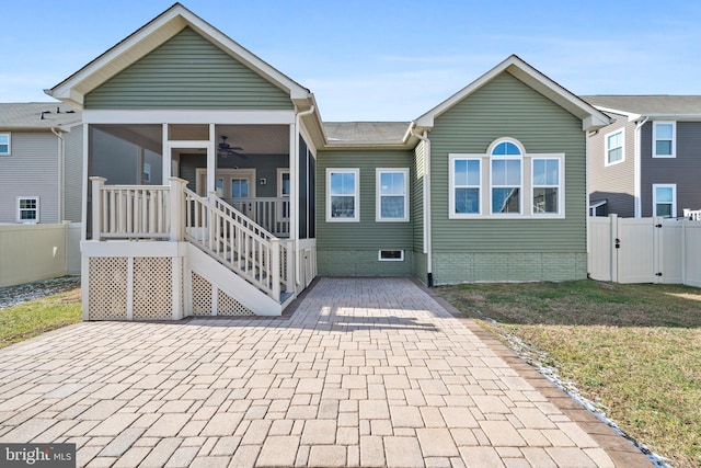 rear view of property with covered porch, ceiling fan, a yard, and a sunroom