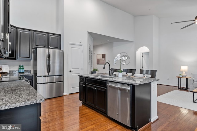 kitchen featuring light stone countertops, sink, appliances with stainless steel finishes, and a kitchen island with sink