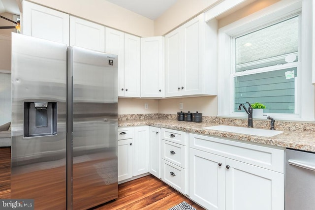 kitchen featuring sink, light stone counters, dark hardwood / wood-style floors, stainless steel appliances, and white cabinets