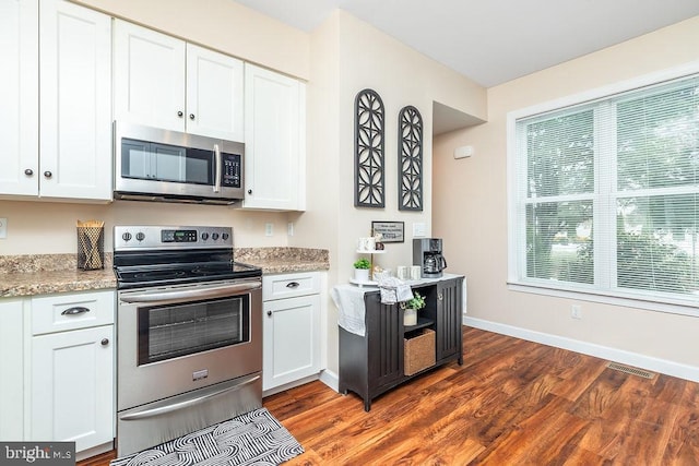 kitchen featuring white cabinetry, stainless steel appliances, light stone countertops, and dark wood-type flooring