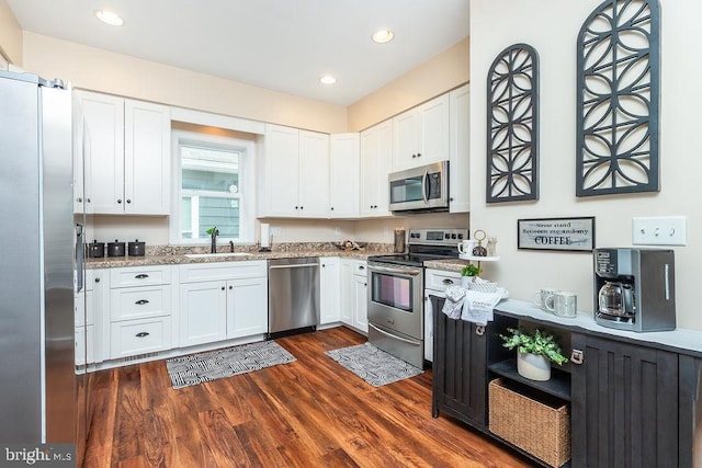 kitchen featuring sink, dark wood-type flooring, stainless steel appliances, light stone counters, and white cabinets