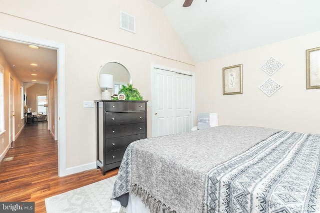 bedroom with dark hardwood / wood-style flooring, vaulted ceiling, ceiling fan, and a closet