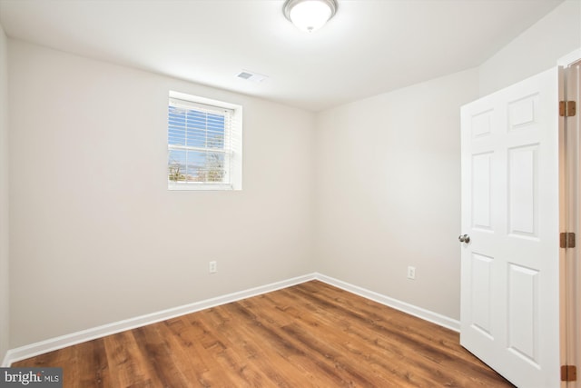 unfurnished room with baseboards, visible vents, and wood finished floors