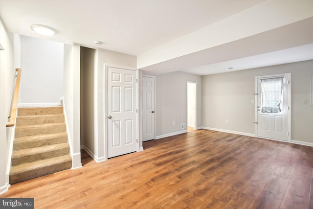 basement featuring stairway, wood finished floors, and baseboards