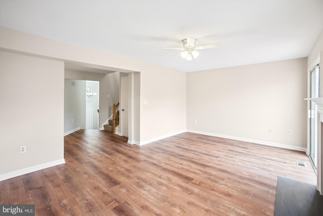 spare room with light wood-type flooring, stairway, baseboards, and visible vents