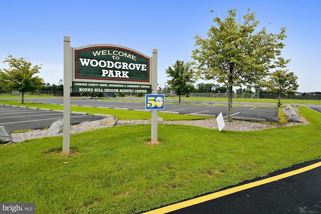 community sign with uncovered parking and a yard