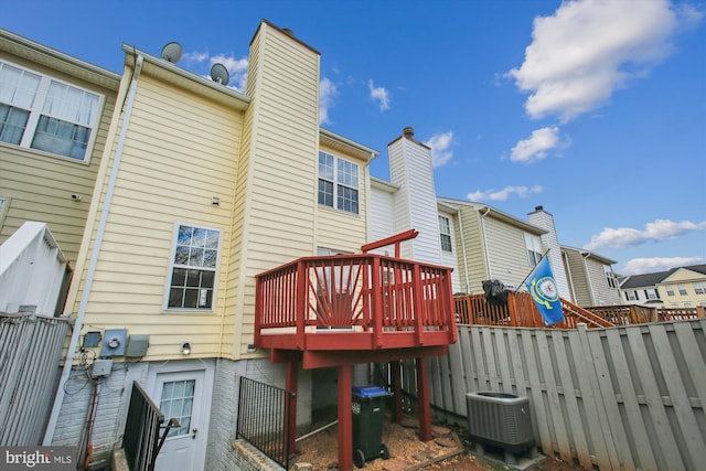 rear view of property with fence, a chimney, a wooden deck, and central AC unit