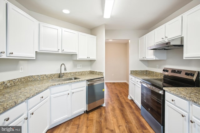 kitchen with appliances with stainless steel finishes, wood finished floors, under cabinet range hood, white cabinetry, and a sink