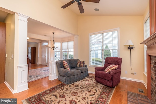 living room featuring lofted ceiling, hardwood / wood-style floors, a fireplace, and decorative columns