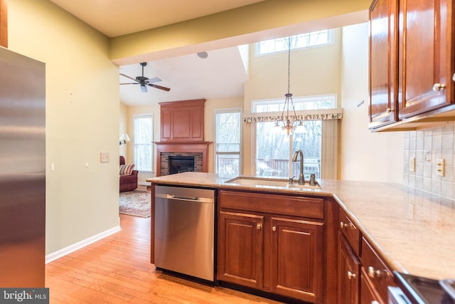 kitchen with stainless steel appliances, a healthy amount of sunlight, tasteful backsplash, a large fireplace, and sink