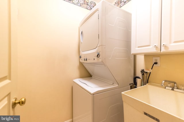 laundry room featuring stacked washer / drying machine and sink