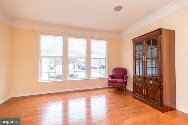 sitting room with crown molding and light hardwood / wood-style flooring