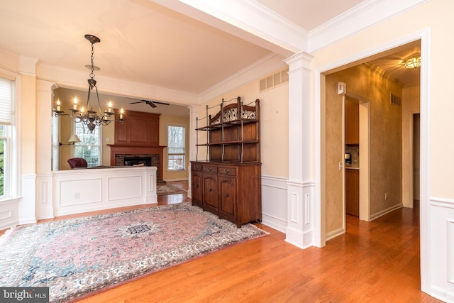 dining area featuring a chandelier, hardwood / wood-style flooring, ornamental molding, and ornate columns