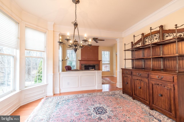 dining room with decorative columns, crown molding, light hardwood / wood-style floors, and a notable chandelier