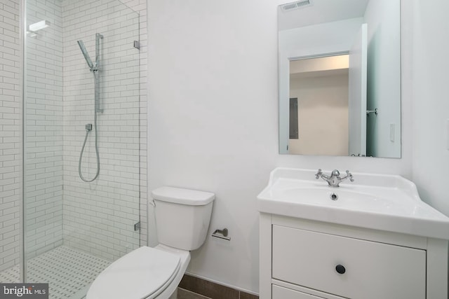 bathroom featuring toilet, vanity, and a shower with door