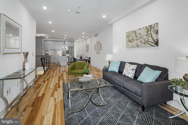 living room with sink, hardwood / wood-style floors, and crown molding