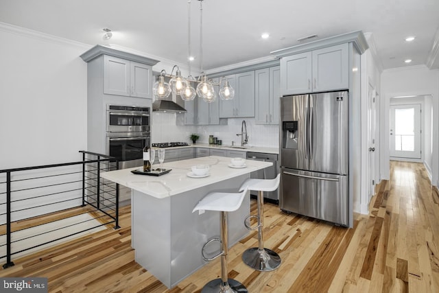 kitchen with appliances with stainless steel finishes, a kitchen island, sink, light stone counters, and a breakfast bar area