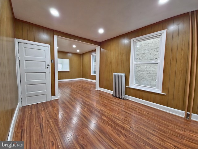 interior space featuring wood-type flooring, radiator, and wood walls