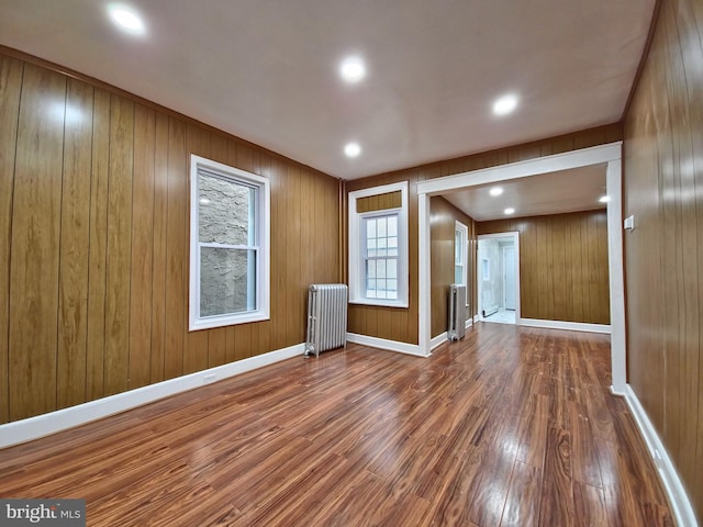 spare room featuring hardwood / wood-style floors, radiator heating unit, and wood walls