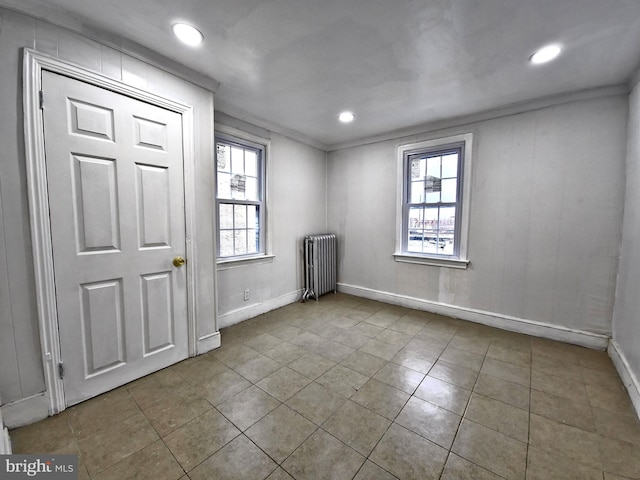 unfurnished room featuring light tile patterned flooring, crown molding, and radiator heating unit