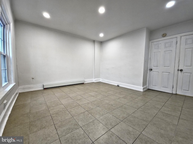 tiled spare room with a baseboard heating unit