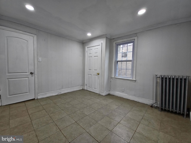 empty room with radiator, crown molding, and light tile patterned flooring