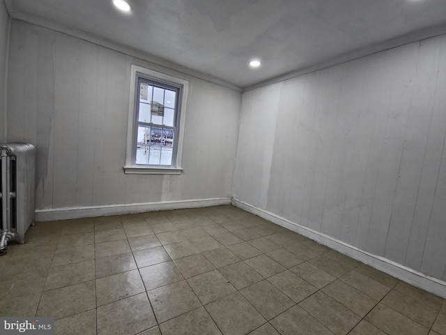 tiled spare room with radiator and ornamental molding