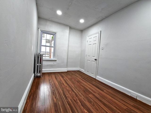 unfurnished room featuring radiator and dark hardwood / wood-style flooring