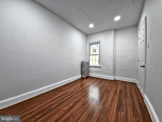 empty room with dark wood-type flooring and radiator