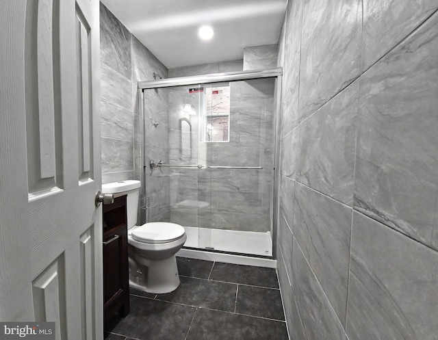 bathroom with toilet, vanity, tile walls, and a shower with door