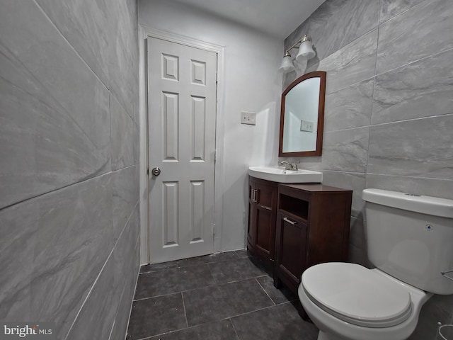 bathroom featuring toilet, vanity, and tile walls