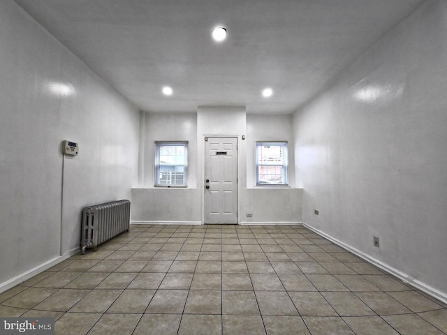 unfurnished room featuring light tile patterned floors and radiator heating unit