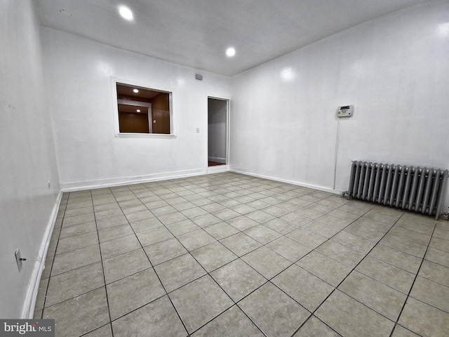 unfurnished room with radiator and light tile patterned flooring