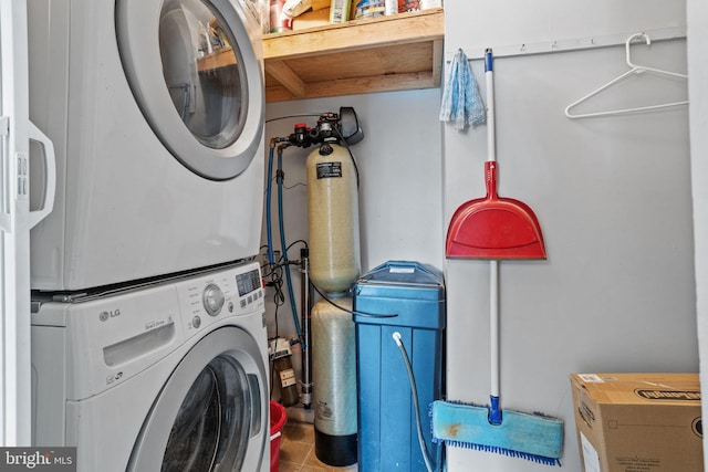 laundry area with stacked washer / drying machine and tile patterned flooring