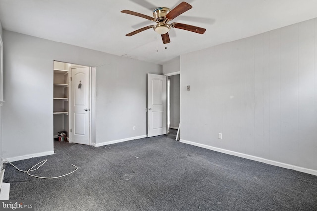 unfurnished bedroom featuring ceiling fan, a closet, a spacious closet, and dark carpet