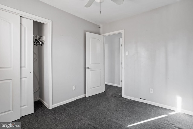 unfurnished bedroom with ceiling fan, dark carpet, and a closet