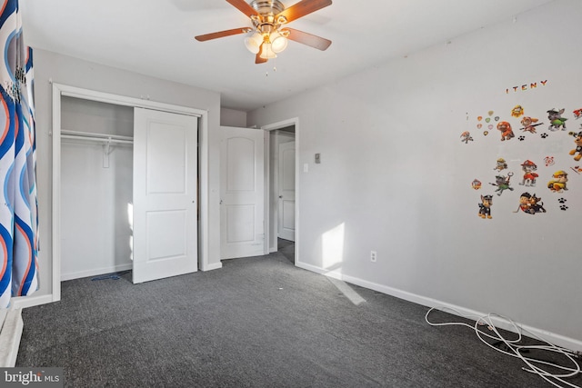 unfurnished bedroom with ceiling fan, a closet, and dark colored carpet