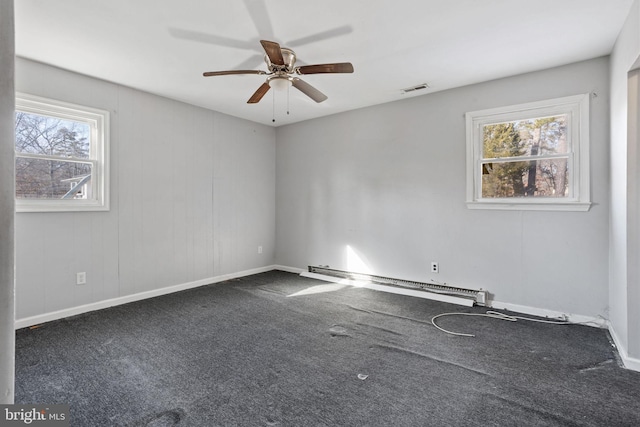 carpeted spare room with ceiling fan and a baseboard heating unit